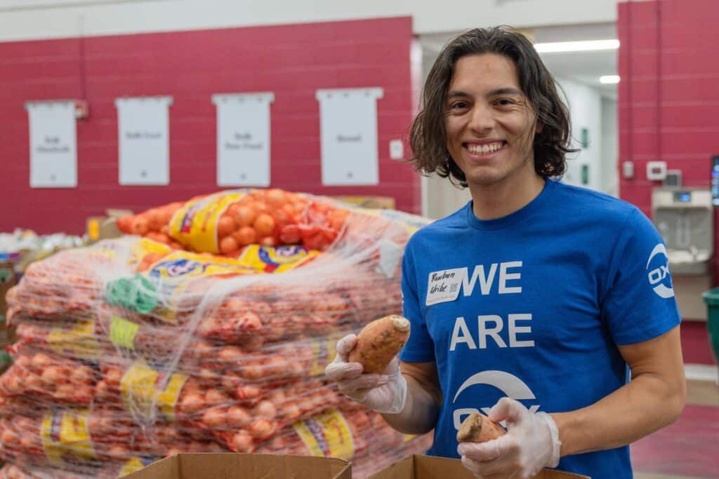 Volunteer in blue shirt in front of pile of produce inside distribution center.