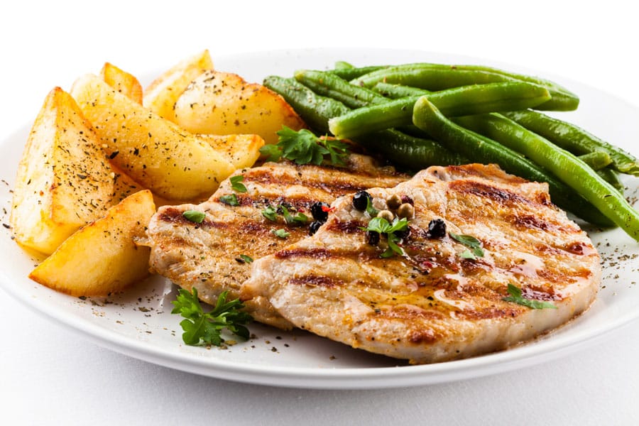 Plate of grilled chicken, green beans, and potatoes, an example of an easy and healthy meal on a budget.