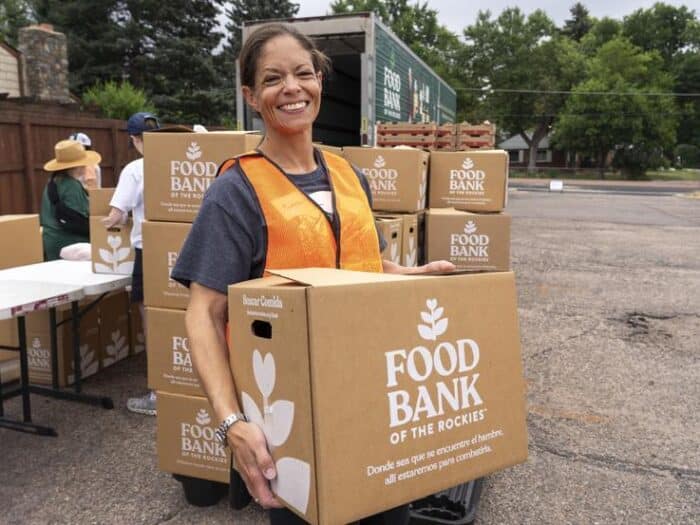 Female volunteer carrying Food Bank box outside at a mobile pantry.