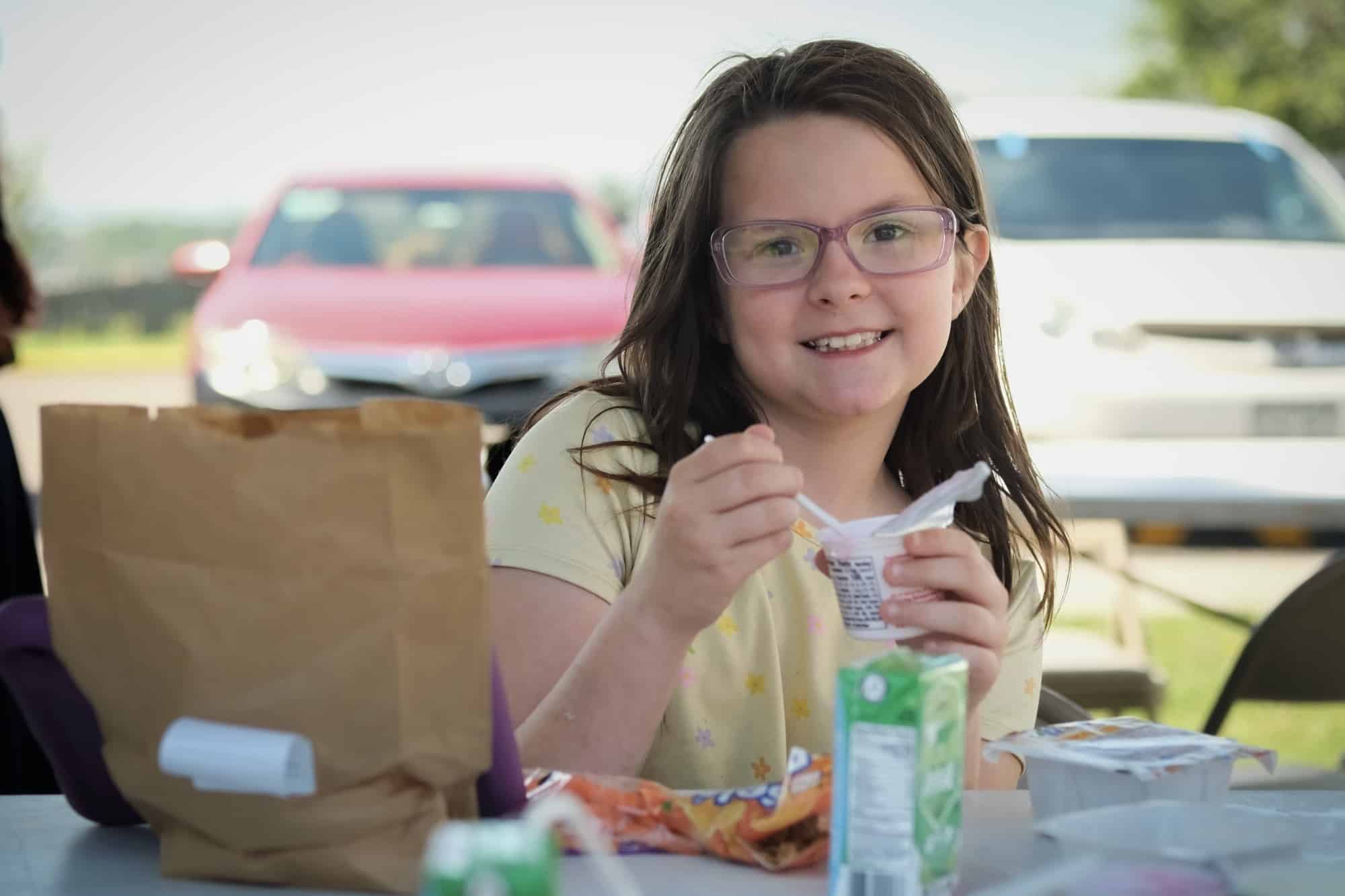 a child eating yogurt outside