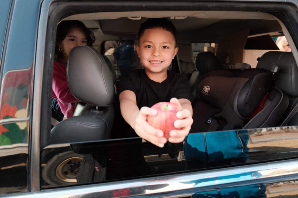 a boy in a car holding an apple