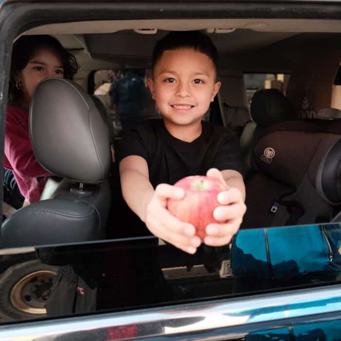 a boy in a car holding an apple
