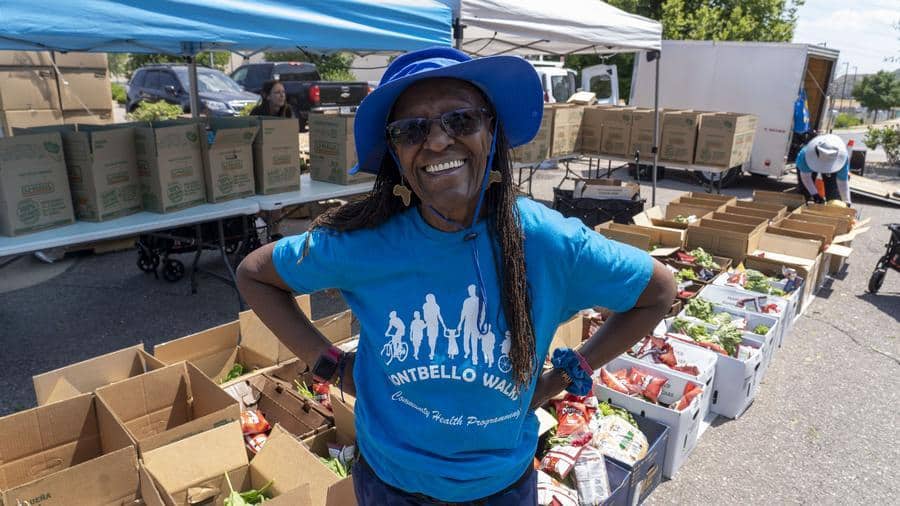 a woman standing outside in front of boxes of fresh produce
