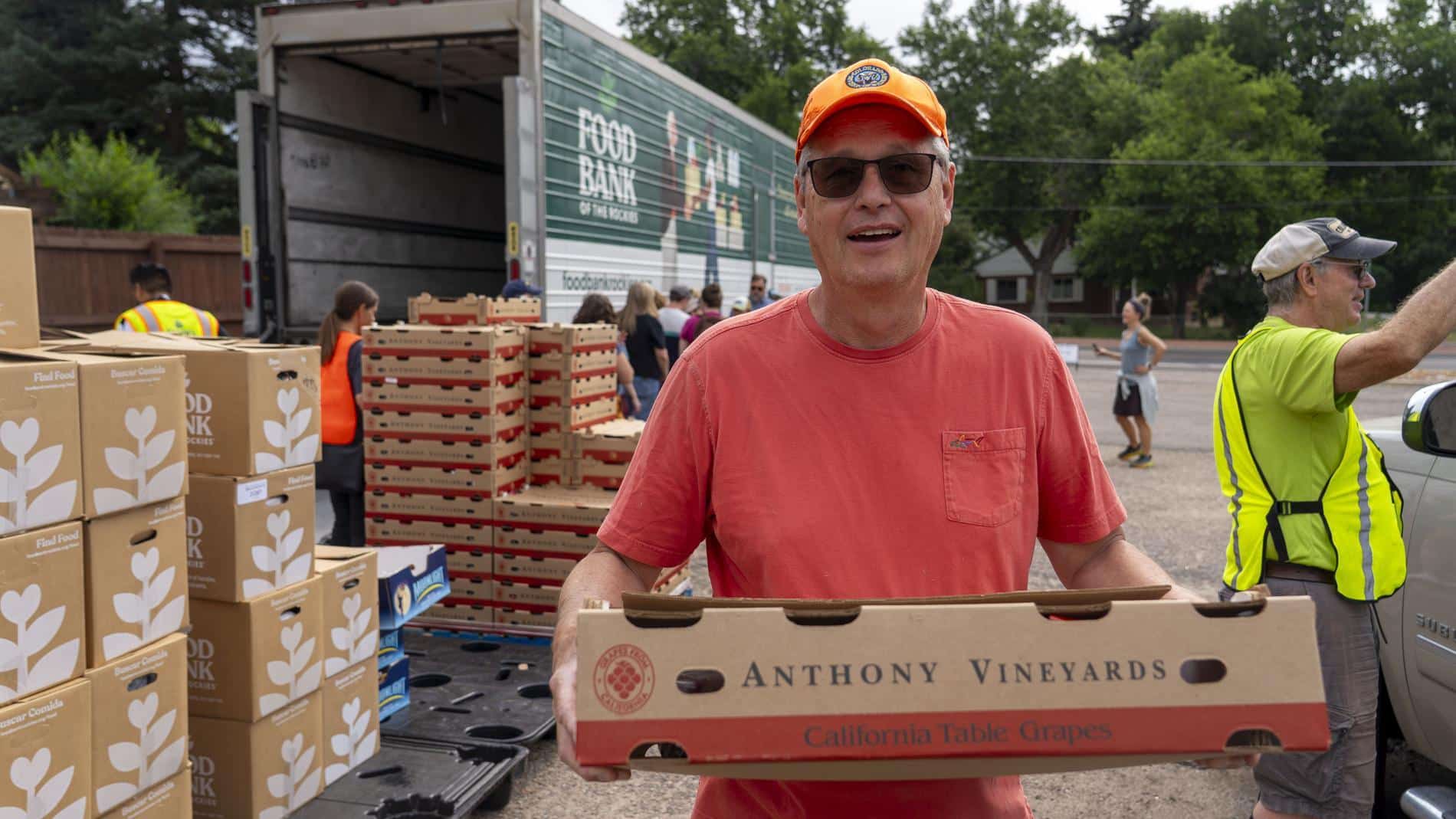 Man holding box of grapes in front of Food Bank truck.
