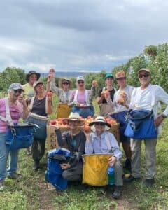 a group of people in an apple orchard holding up apples