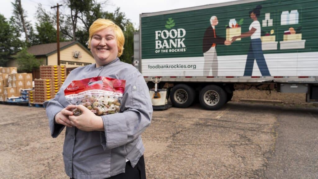 a person standing in front of a Food Bank of the Rockies trailer