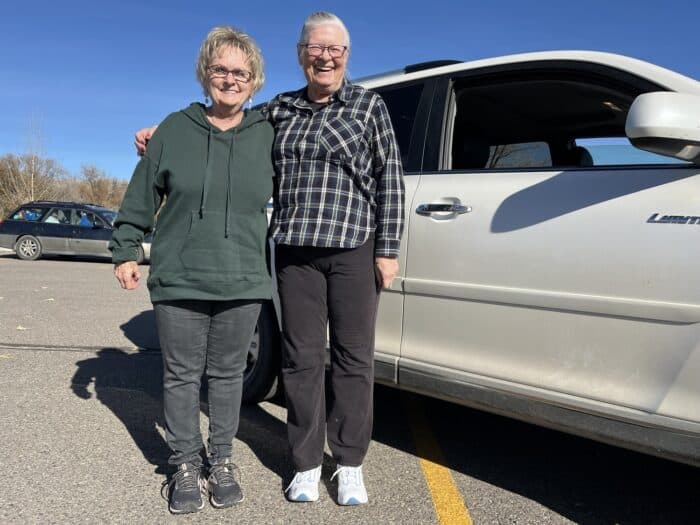 Two people standing in a parking lot outside of a car