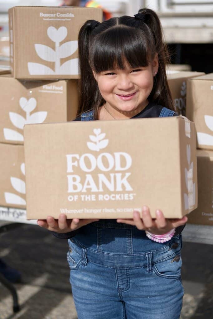 a little girl holding a Food Bank of the Rockies box