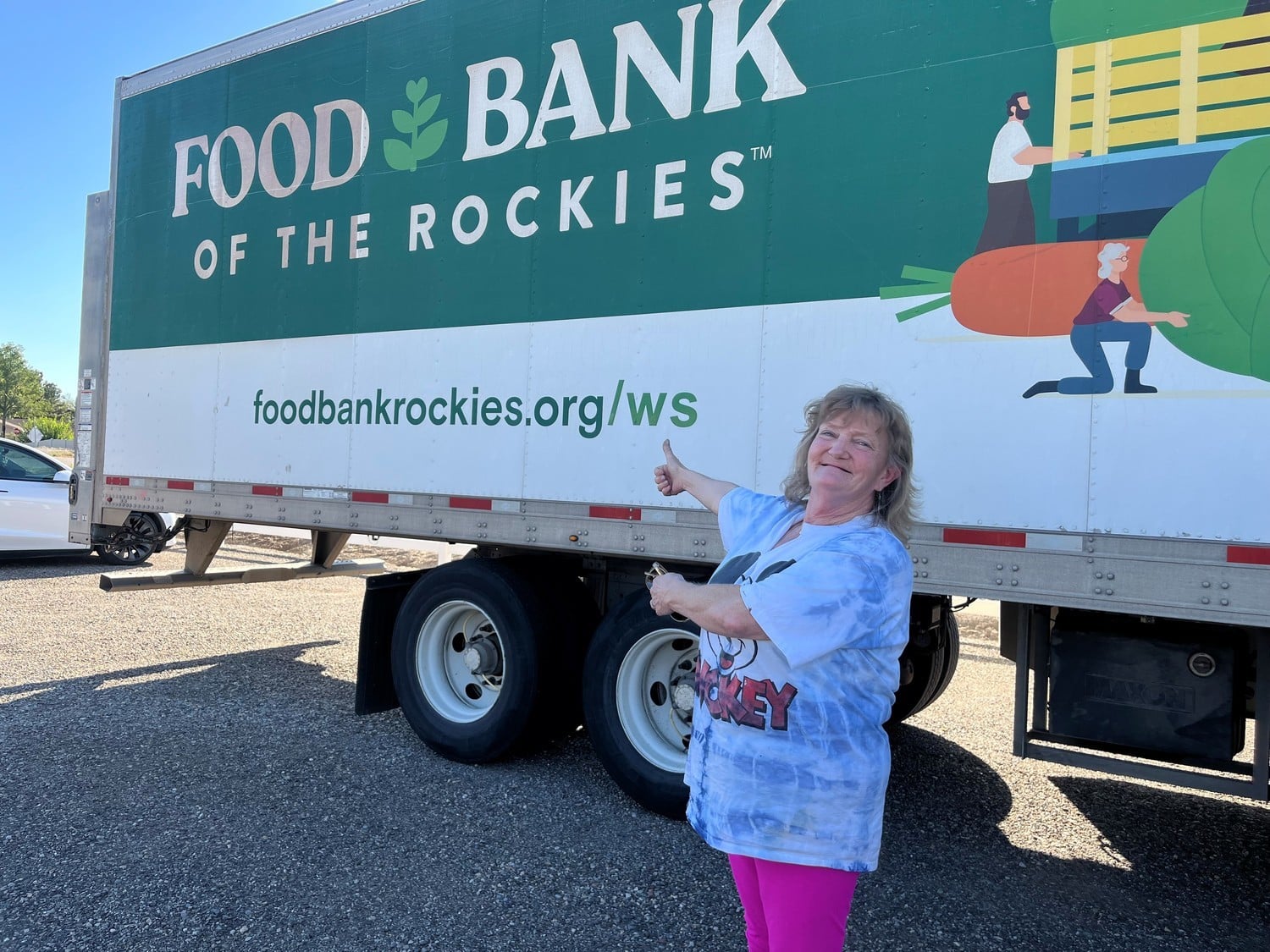 Gretchen standing in front of Food Bank of the Rockies truck pointing to it.