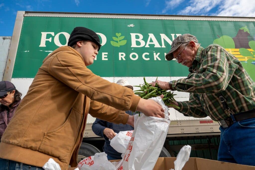 volunteers gather fresh green beans and bag them. Standing in front of Food Bank of the Rockies green truck.
