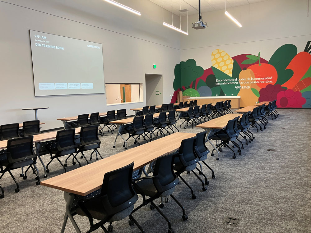 Training room configured with rows of tables and chairs, projection screen.