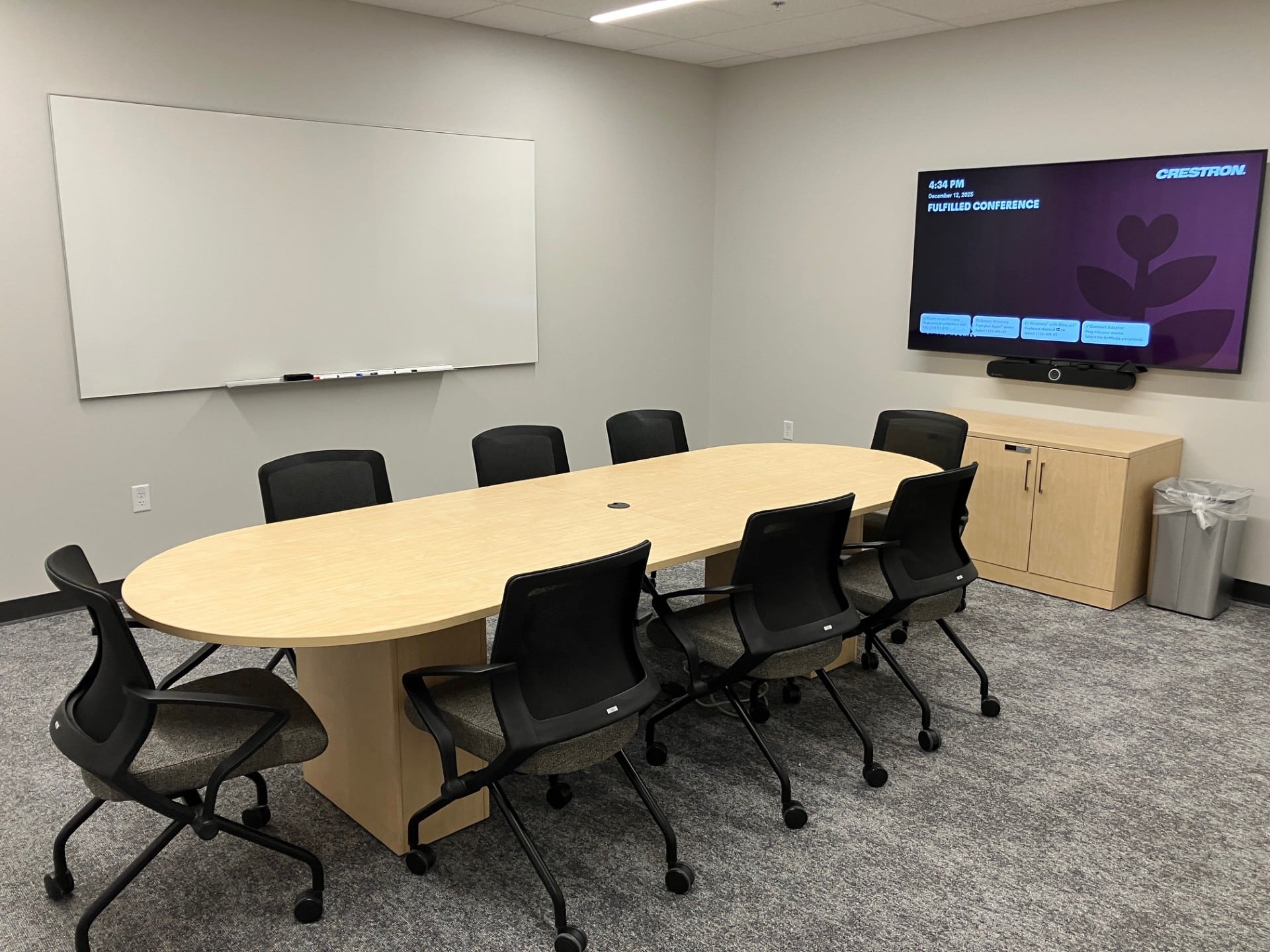Fulfilled meeting room with table, chairs, TV, and whiteboard