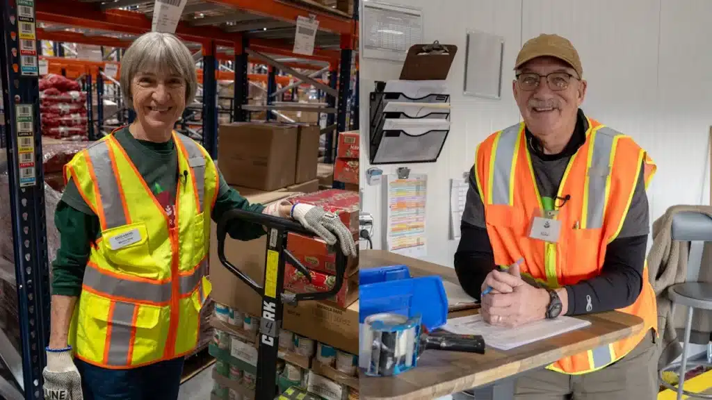 Martha King and Mike Kenyon posing wearing safety jackets in the warehouse of the new distribution center.