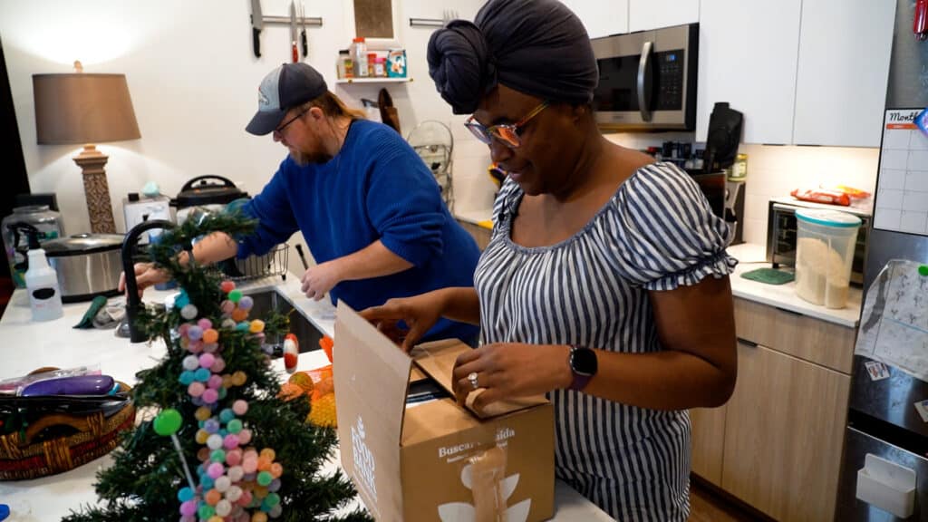 Adam and Hannah opening a box in a kitchen