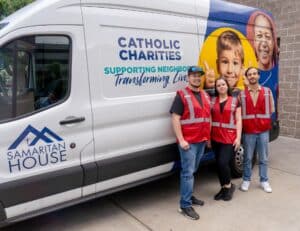 Volunteers standing in front of a Samaritan House van.