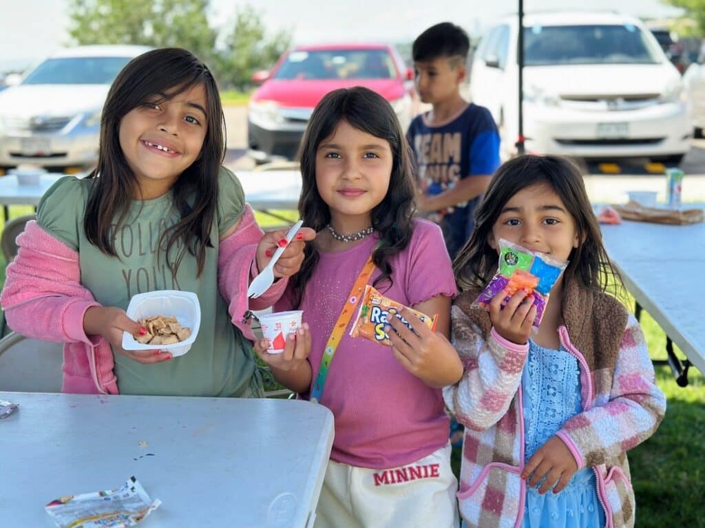 three girls holding snacks outside.