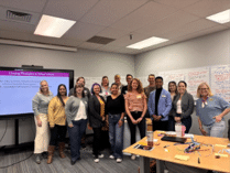 Large group of staff posing for picture inside conference room.