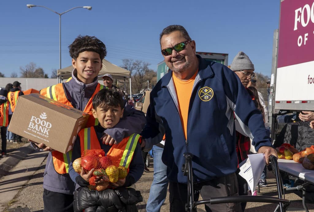 A teen and younger boy holding boxes on the left, with an adult neighbor on the right.