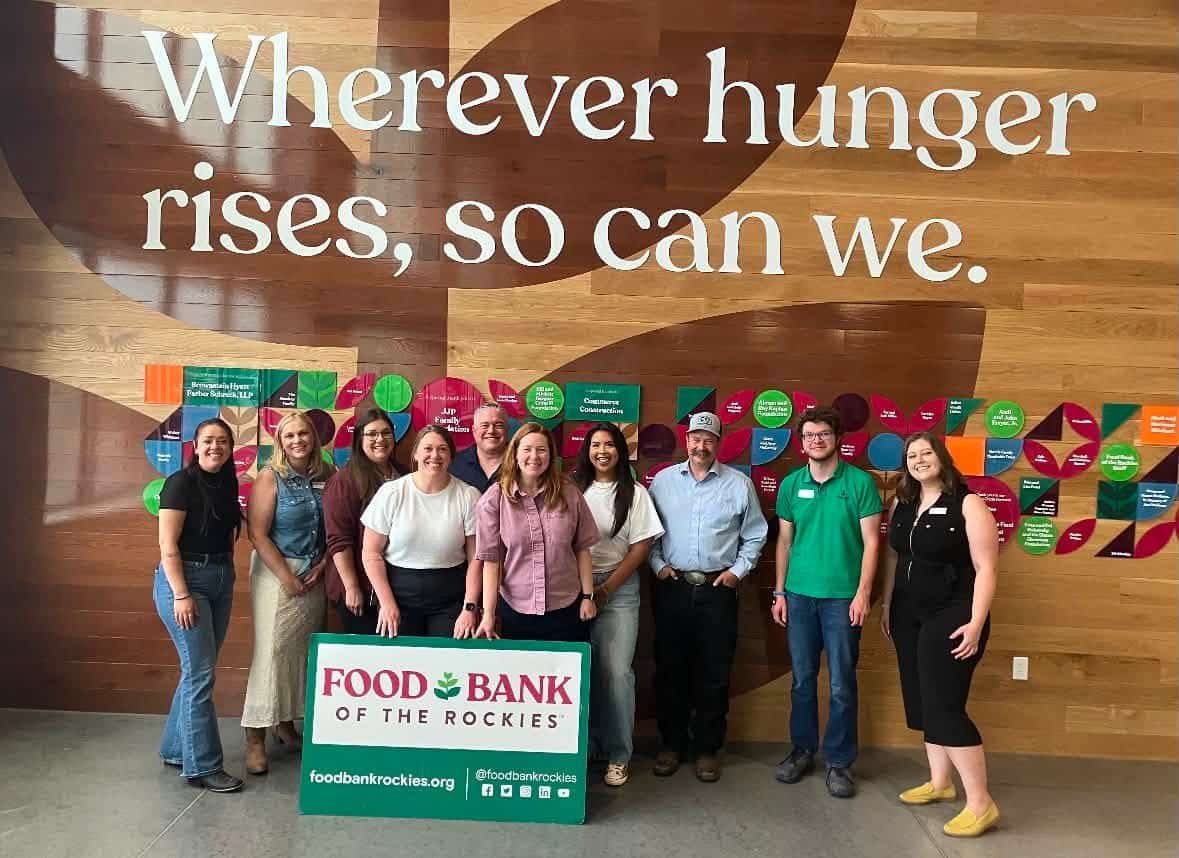 a group of people standing in front of the 'wherever hunger rises, so can we' signage