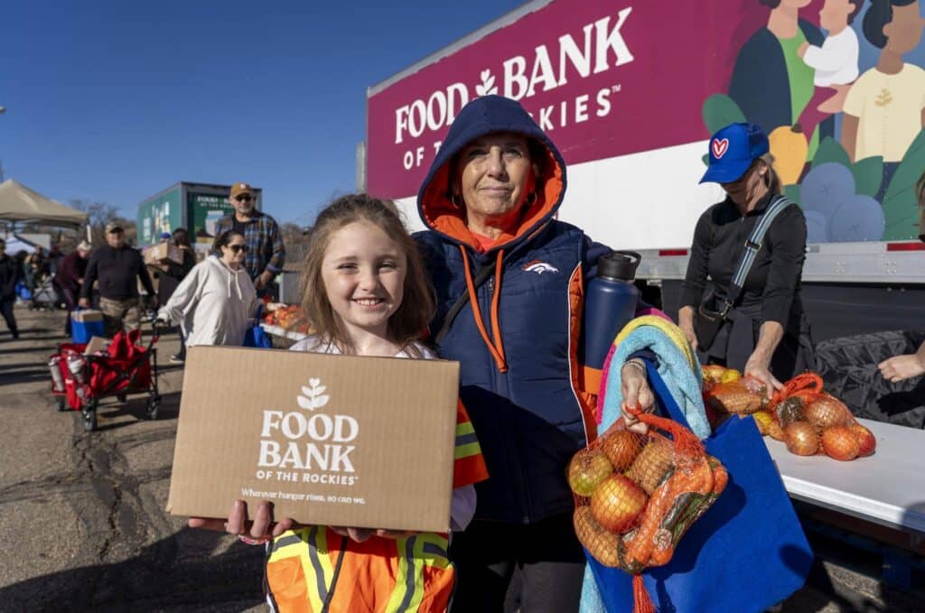 a woman and a child holding boxes and bags of food during Thanksgiving